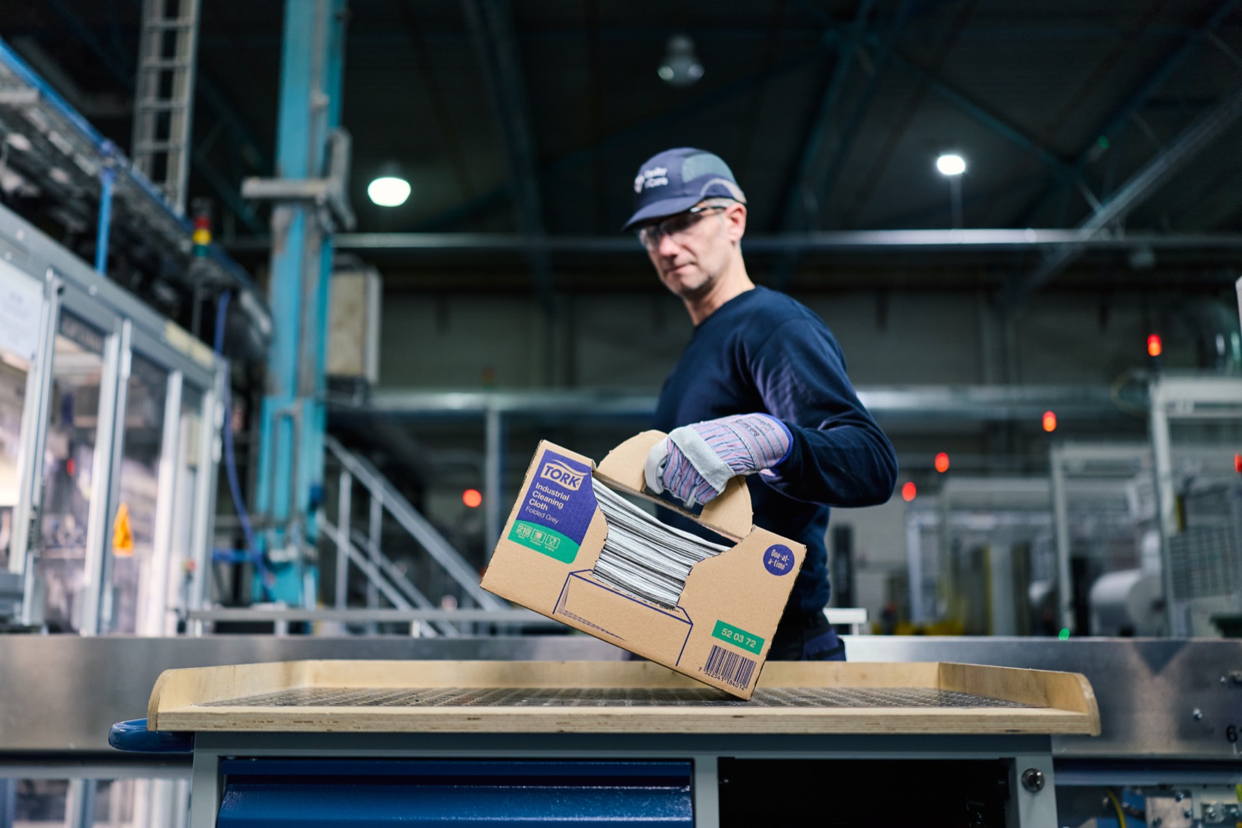 Medewerker met een doos Tork Industrial Cleaning Cloth in de fabriekshal